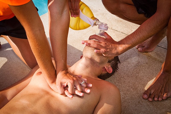 CPR, Man receiving cardiopulmonary resuscitation close to a pool